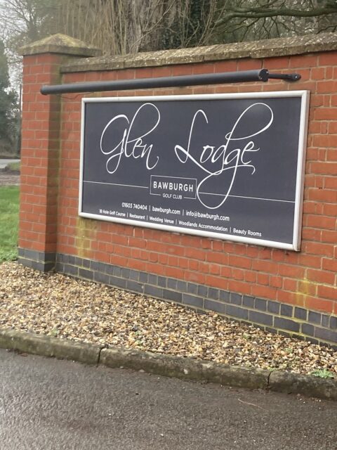 A sign on a brick wall displays "Glen Lodge Bawburgh Golf Club" with contact information and services listed below.